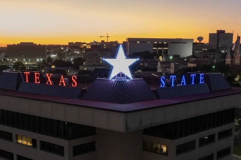 The Victory Star glows on top of the JC Kellam building. The words "texas state" and the star are in a red, white, and blue design.
